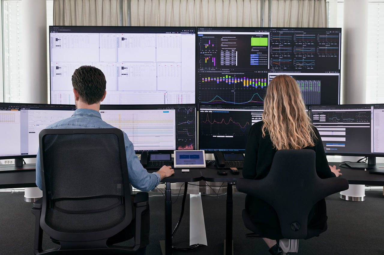 To mennesker sitter jobber på mange skjermer